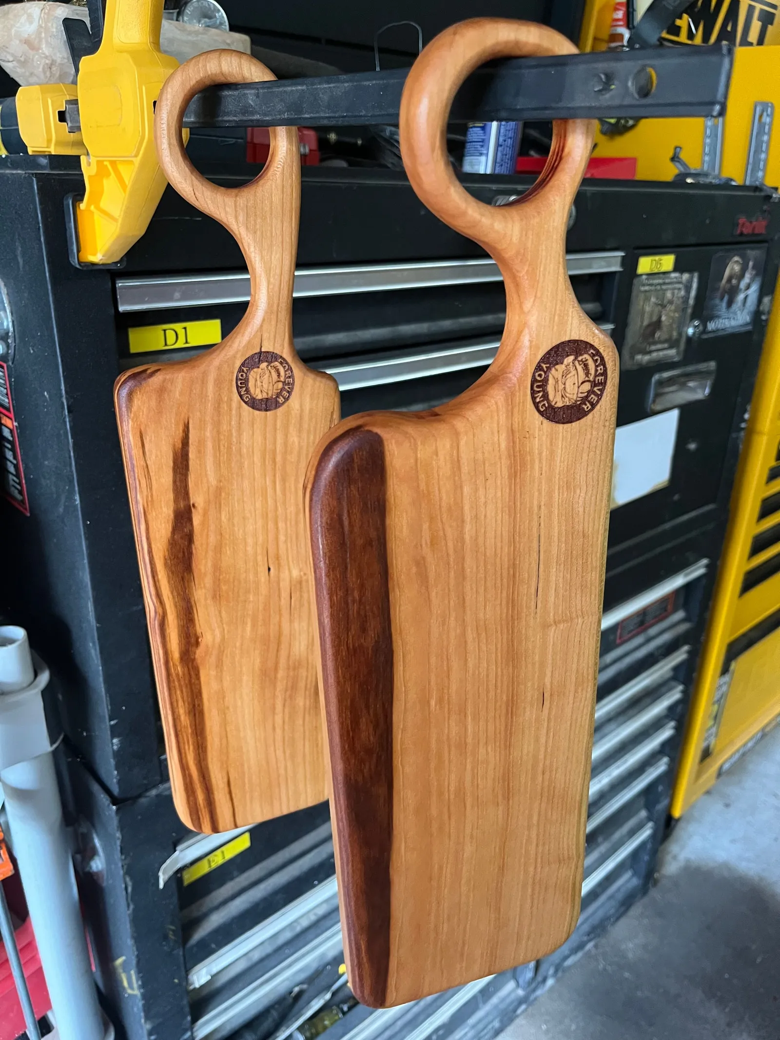 Two wooden paddle boards hanging on a tool chest.