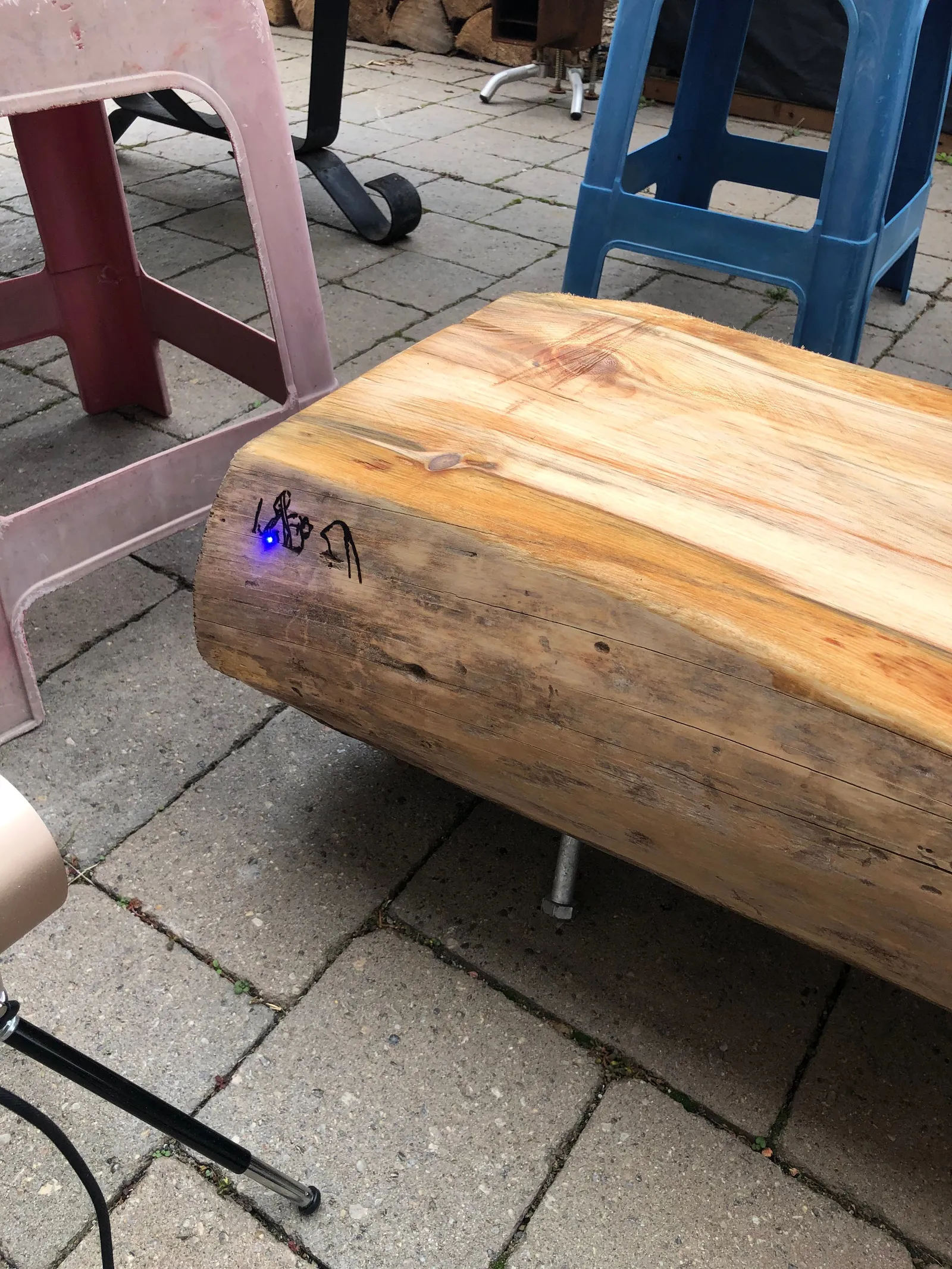 A live-edge wood slab used as a bench on a patio.