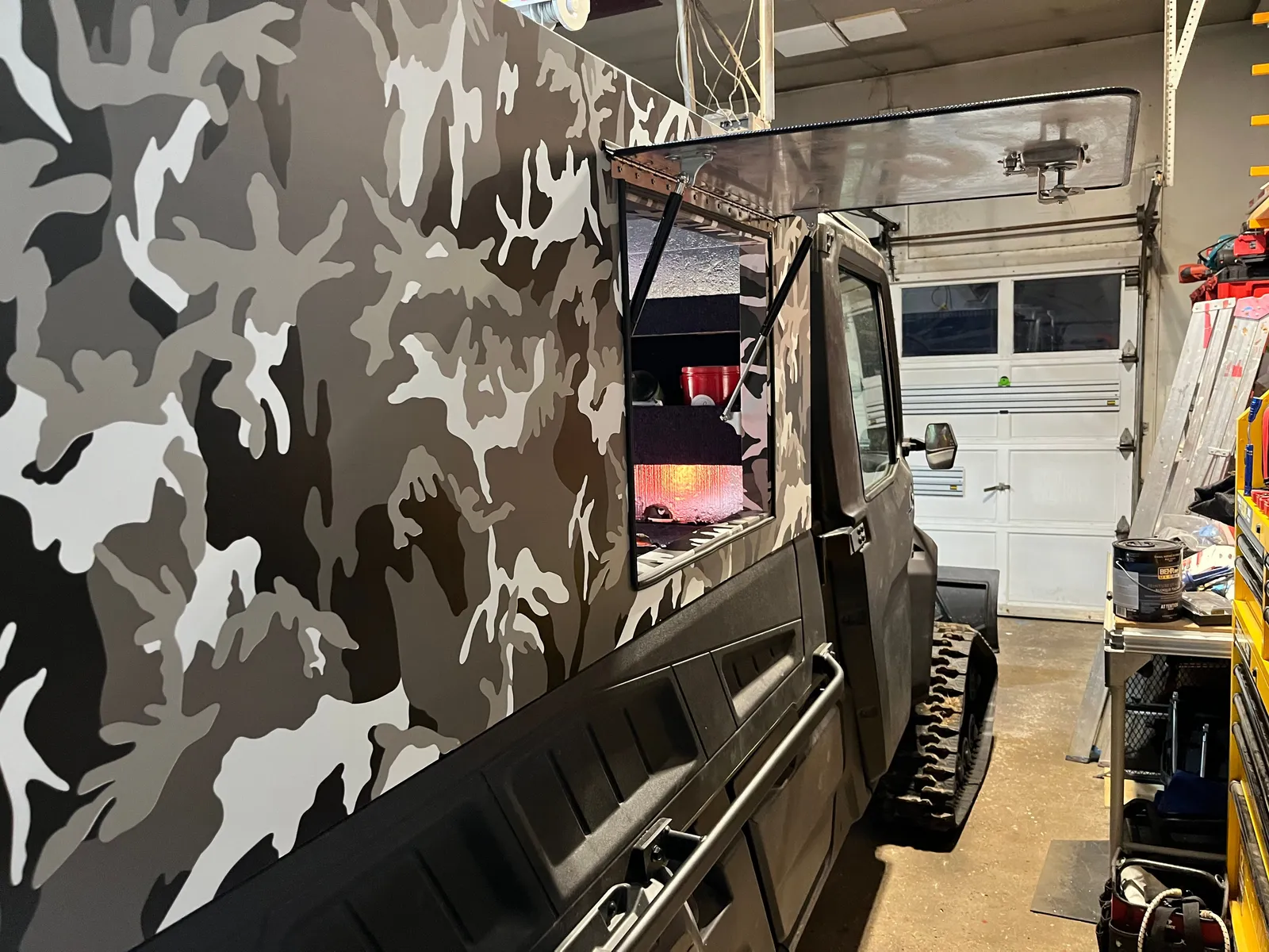 A camouflage-wrapped cabin side panel, in a garage.