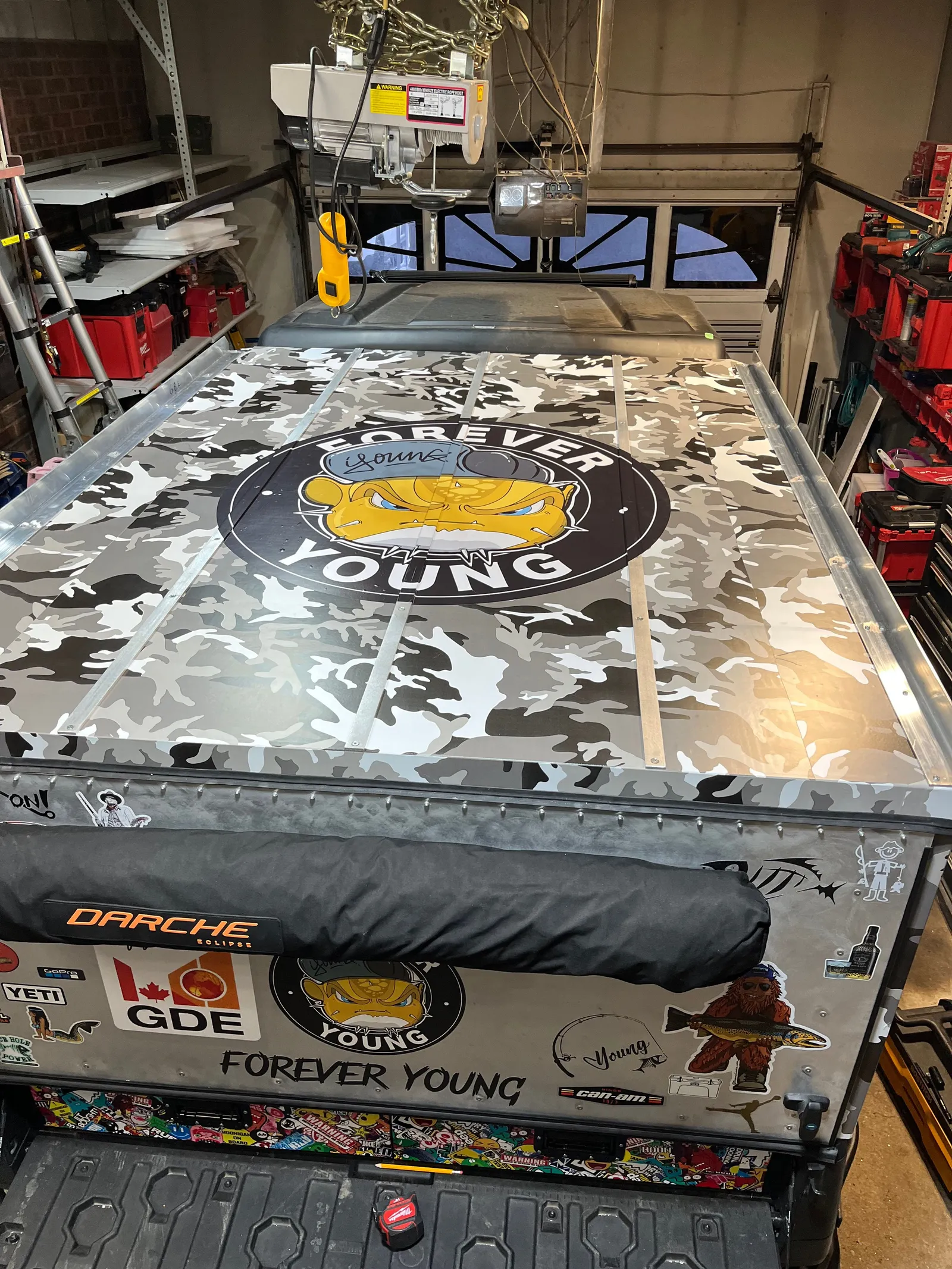 A camouflage-wrapped hatch lid with a round logo.